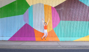 This is a colourful wall with a happy lawyer jumping in front of it.